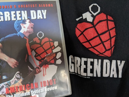 American Idiot: The Ultimate Critical Review dvd cover next to a Green Day concert t-shirt